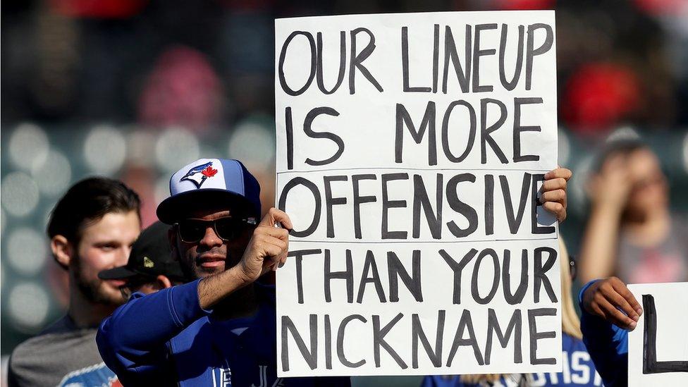 A Toronto Blue Jays fan holds up a sign that reads, 'Our Lineup Is More Offensive Than Your Nickname'