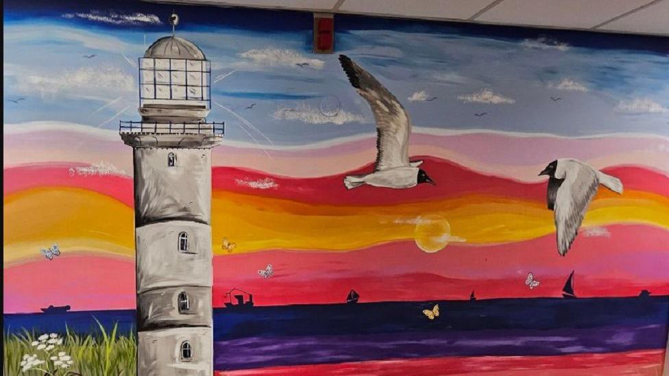 Another wall featuring a colourful sunset, a lighthouse and birds