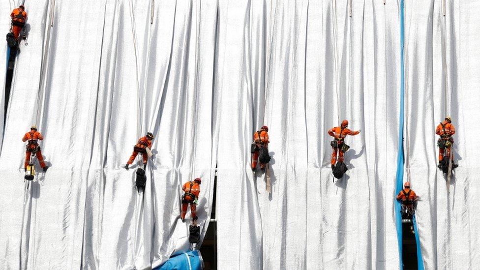 Workers install a shimmering wrapper to envelop Paris landmark, the Arc de Triomphe