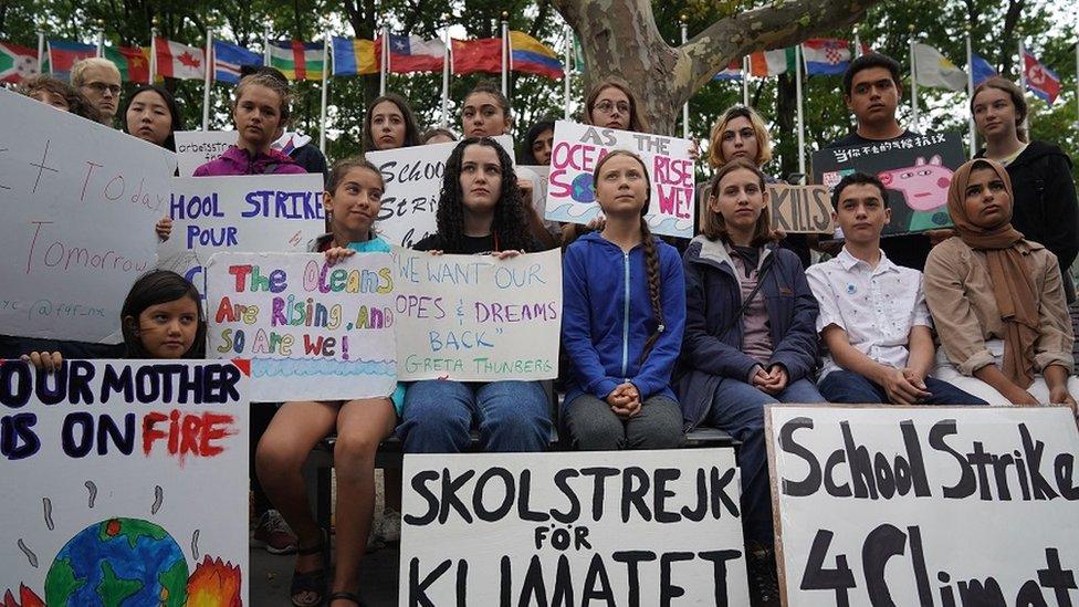 Greta sitting with school children on strike