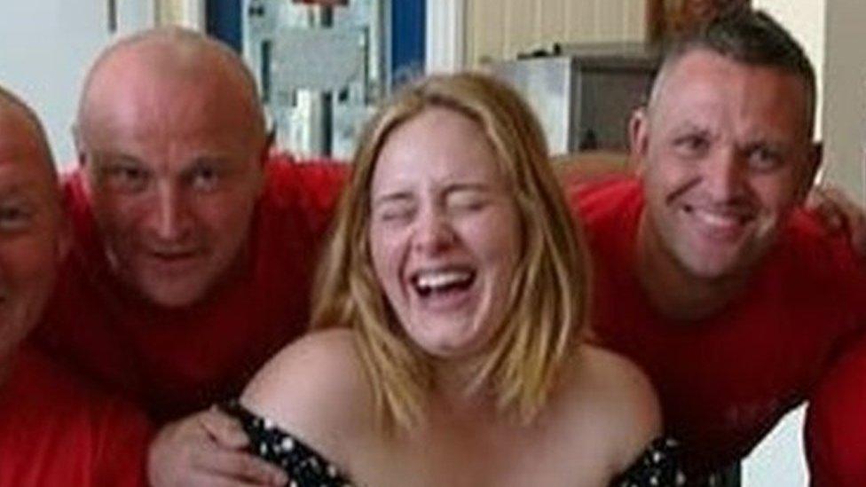 Picture of a laughing Adele with firefighters