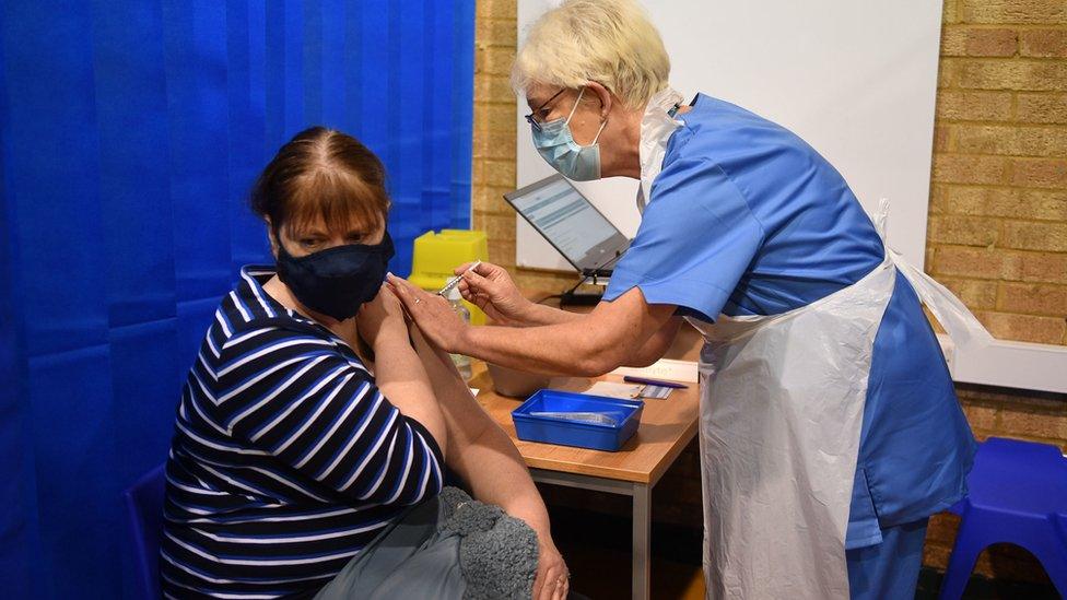 A nurse administering a vaccine to a woman