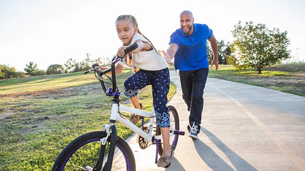 parent helping kid cycle