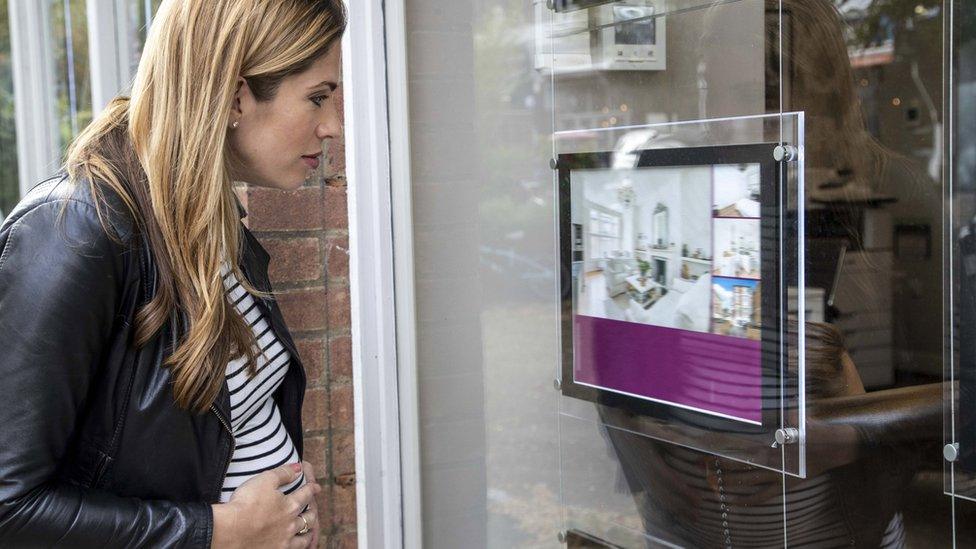 pregnant woman looks in estate agency window