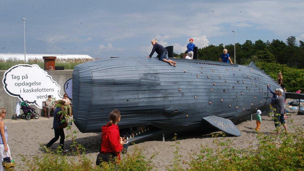 Children playing on a large climbing structure shaped like a sperm whale