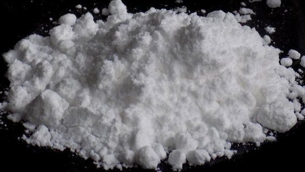 A white powder in a pile on a black surface.