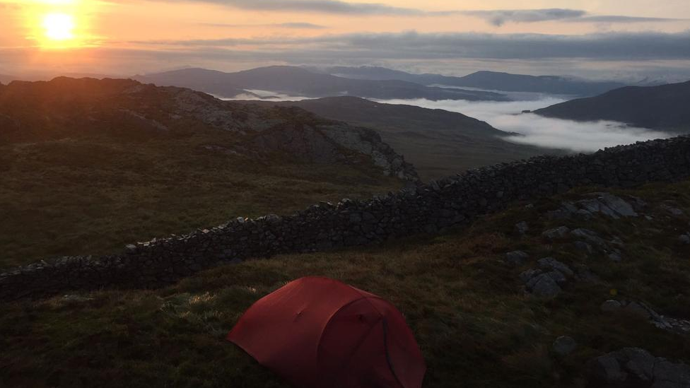 A tent with a sunrise in the background