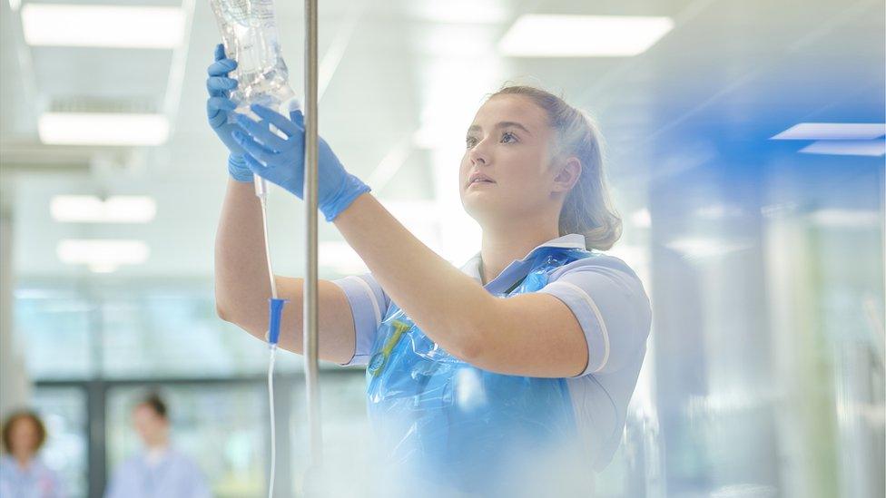 A nurse inspects a drip