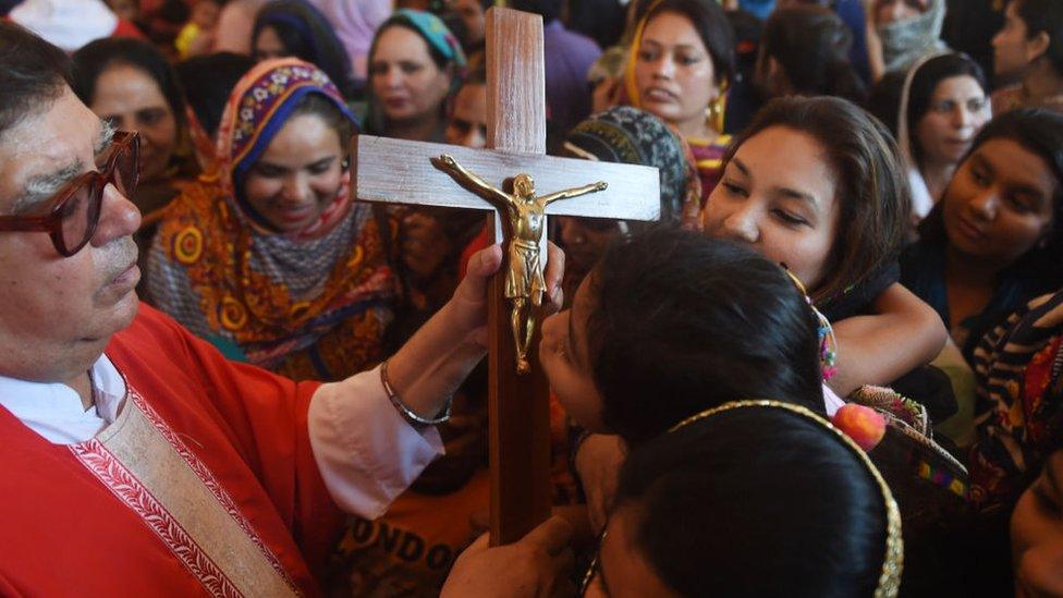 Pakistani Christians devotees kiss a depiction of the crucifixion of Jesus during a Good Friday service at St Anthony's church in Lahore on April 19, 2019. (