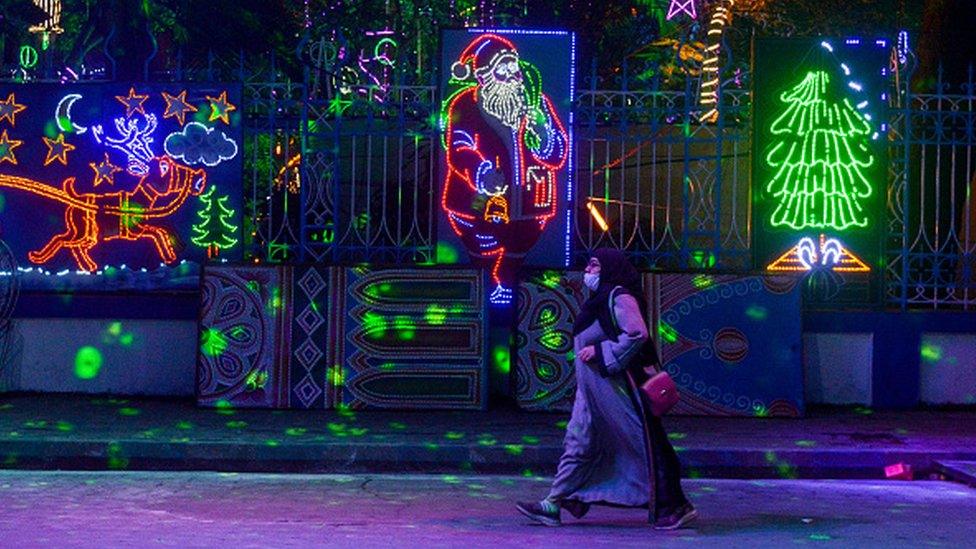 A lady walks past a lighted decoration showing Santa Clause ahead of Christmas celebration in Kolkata , India