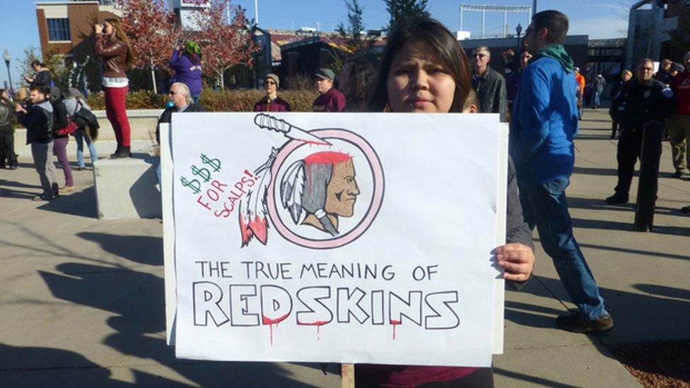 A person at a protest in Minnesota holding up a sign criticising the use of the world "redskin" in 2014