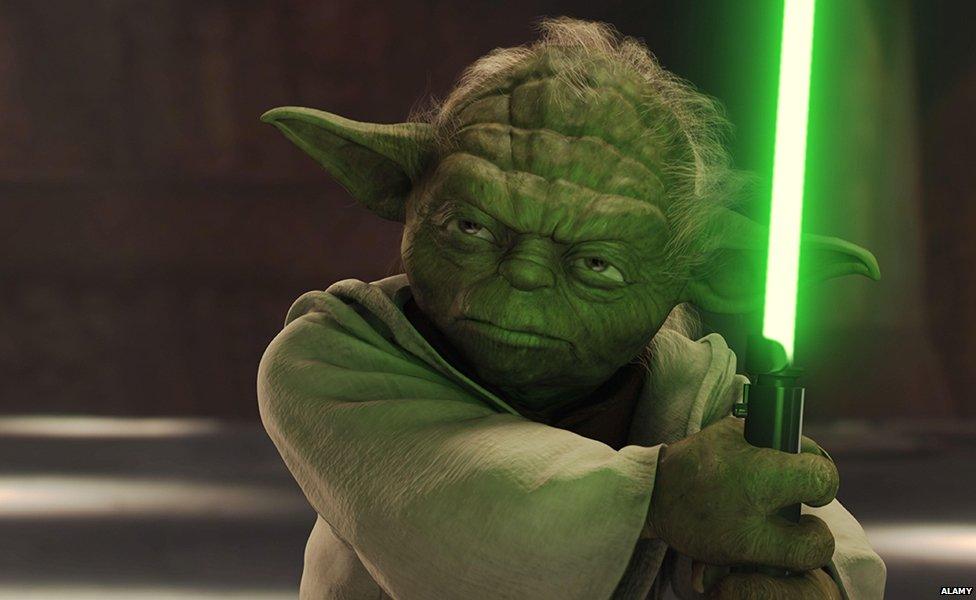 Yoda wielding a lightsaber