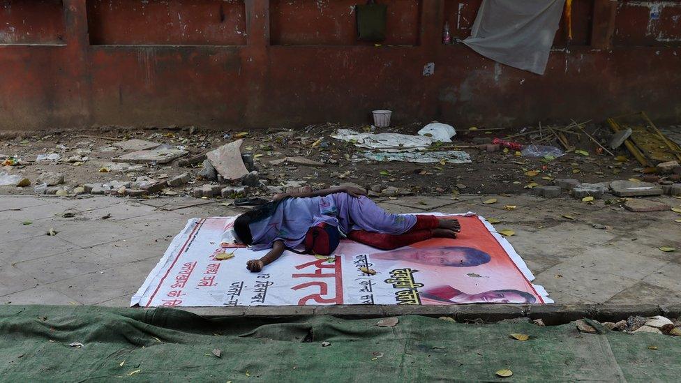 A homeless Indian woman sleeps on the side of a footpath in New Delhi on August 18, 2015