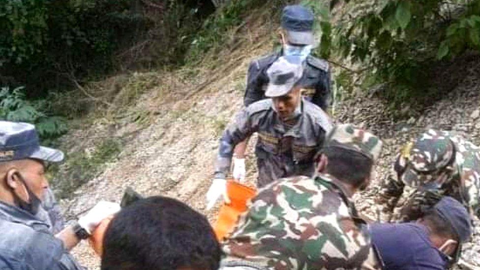 Rescue workers and local people work at the site of a passenger bus crash in Mugu district, Nepal, 12 October 2021