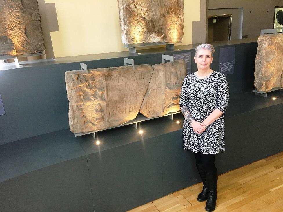 Dr Louisa Campbell in The Hunterian with the Summerston distance stone from the Antonine Wall