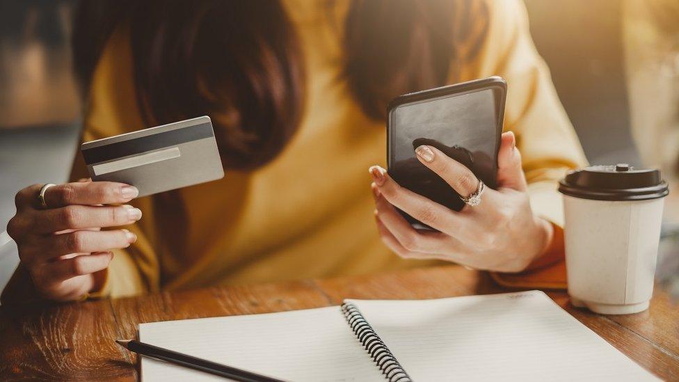 Woman looking at mobile phone and credit card