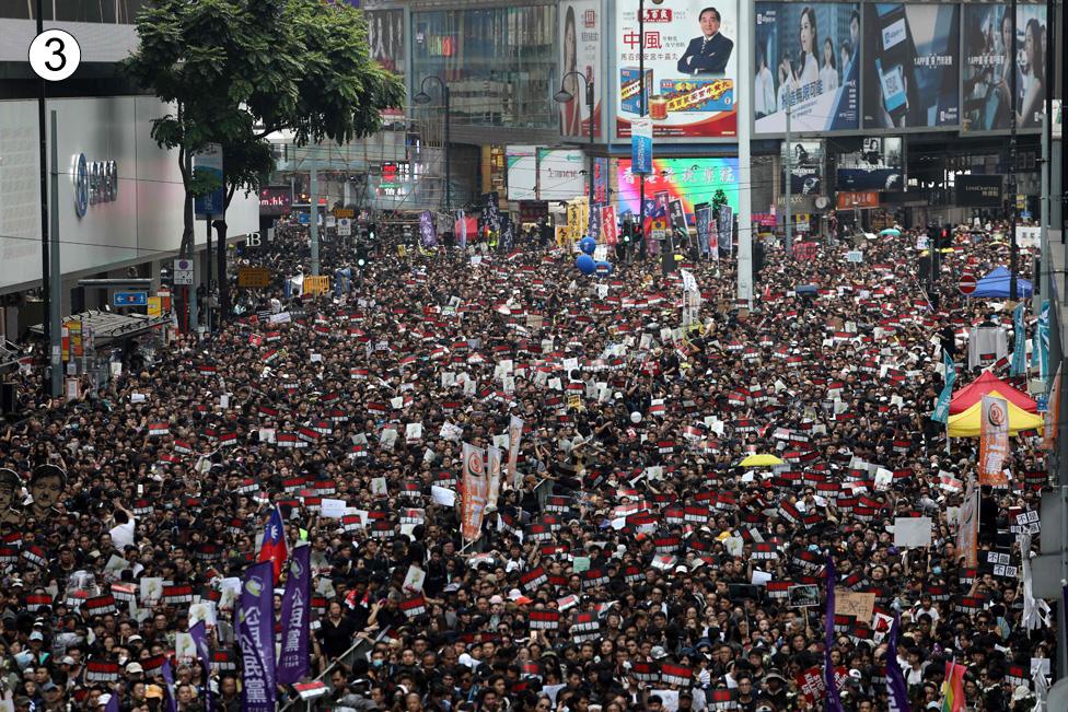 The Sogo deparment store, left, can be seen amid the huge crowd as the road parts in a V shape behind them