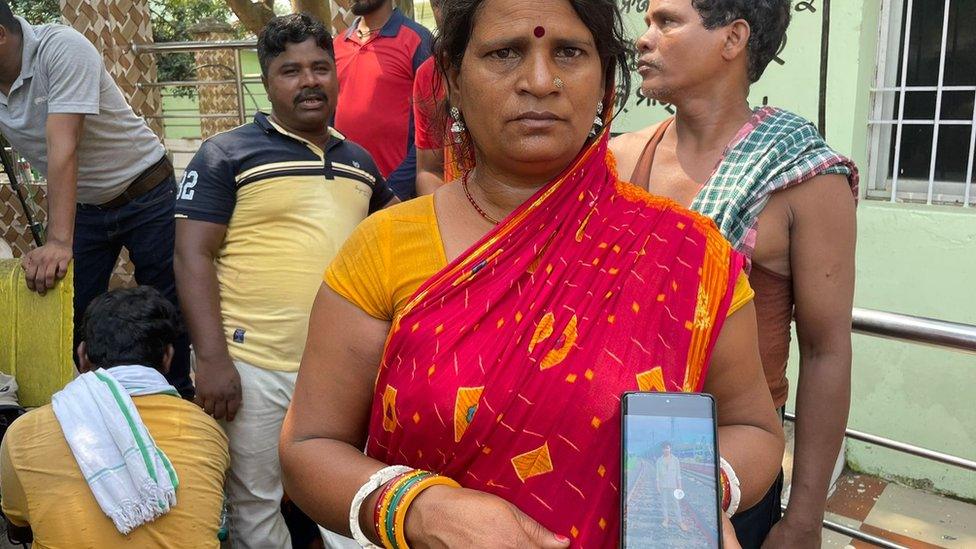 Lilavati Devi holds up a mobile phone with a photo of her missing son