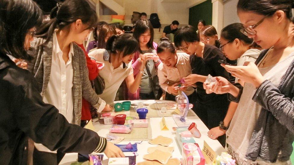 Women look at different menstrual cups with enthusiasm during a promotional event in Taipei