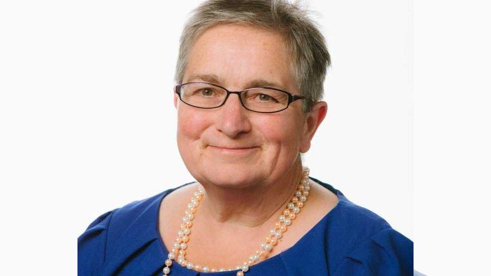 Head and shoulders shot of Councillor Cheryl Payne. She is wearing a blue top, a necklace and spectacles. She has short hair.