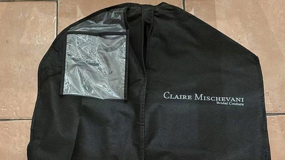 Image of a black garment bag with the designer's name printed on them.