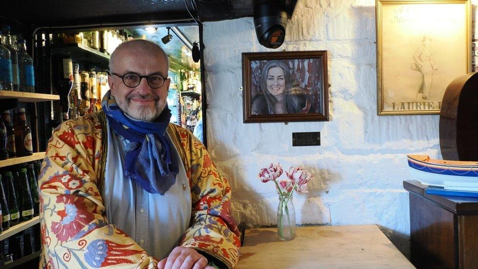 HH Judge Ian Lawrie KC standing next to a picture of Polly Higgins KC in the Woolpack pub