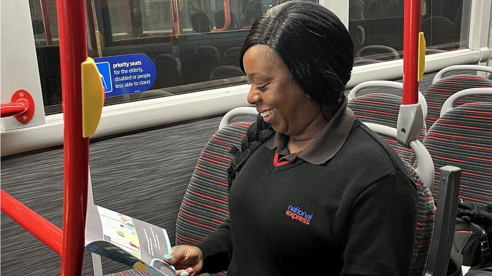 A female bus driver looking at a book