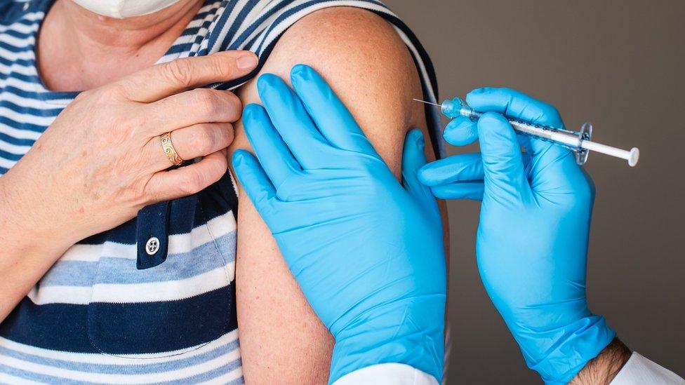 Close shot of a woman receiving a vaccination at the top of her arm