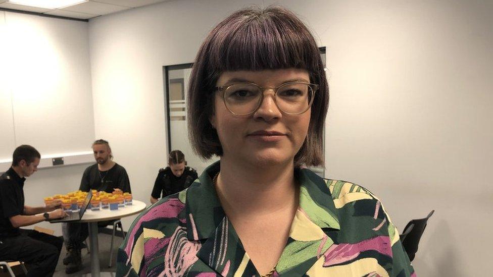 A woman with a dark bob and in a brightly coloured shirt and glasses