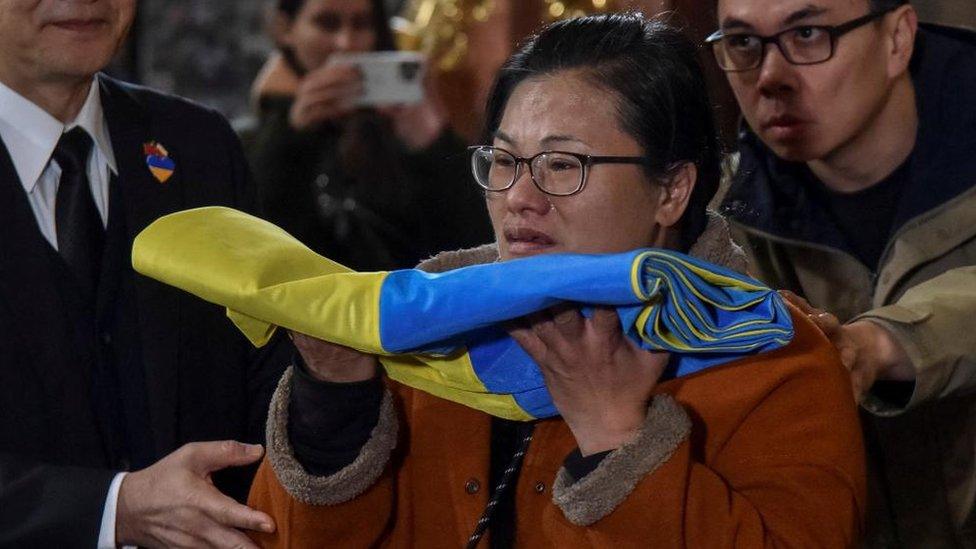 Jonathan Tseng's mother holds a Ukraine flag