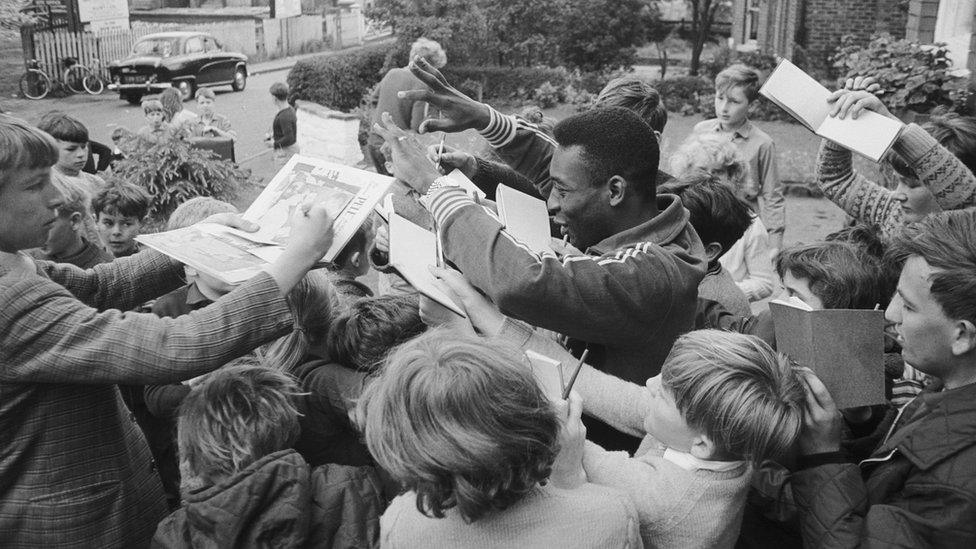 Brazilian football star Pele signing autographs outside the team hotel in Lymm, Cheshire, during the 1966 World Cup in England, July 1966. (Photo by Central Press/Hulton Archive/Getty Images)