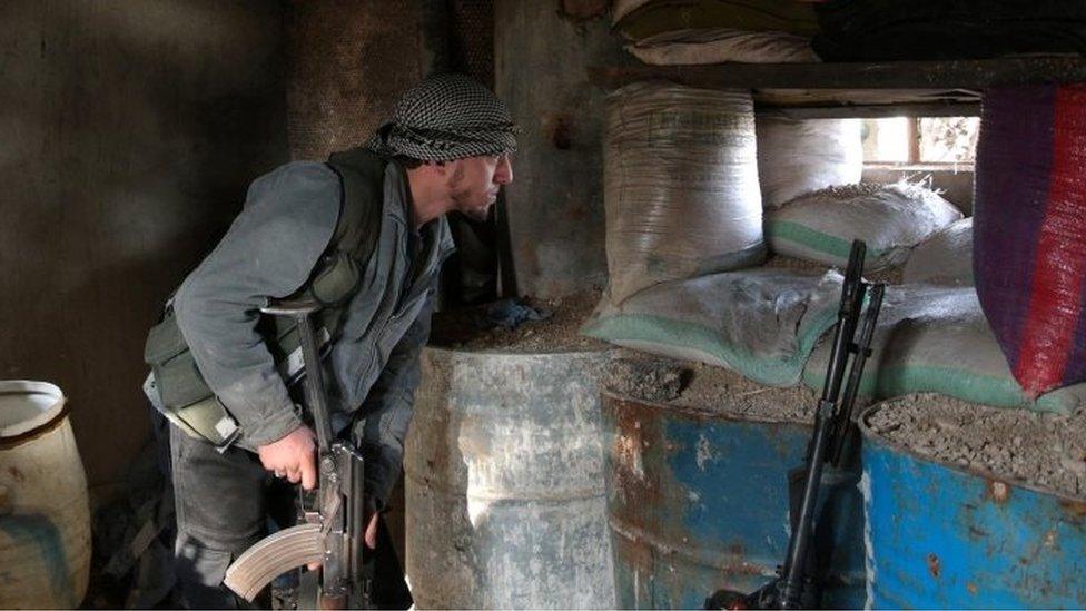 A rebel fighter looks out through sandbags on the forth day of the truce, on al-Rayhan village front near the rebel held besieged city of Douma, in the eastern Damascus suburb of Ghouta (02 January 2017)