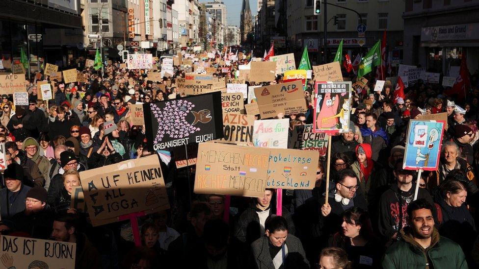 Dozens of protesters in Dusseldorf holding anti-far right slogans in German