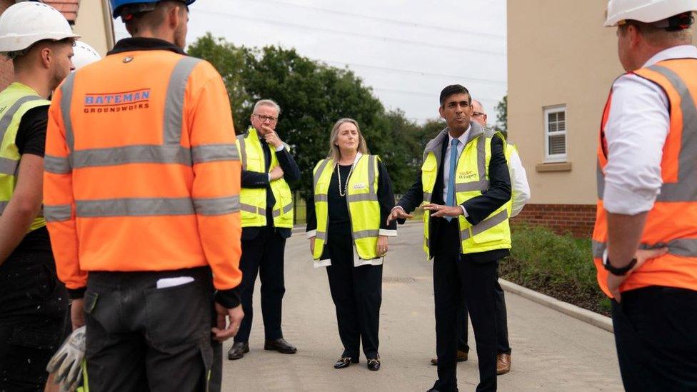 The PM Rishi Sunak talks to builders at a housing estate in Hethersett, Norwich