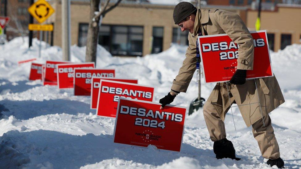 A volunteer plunges campaign signs for Republican Presidential Candidate, Florida Gov. Ron DeSantis into deep snow outside the Chrome Horse Saloon one day before the Iowa caucuses on January 14, 2024 in Cedar Rapids, Iowa.