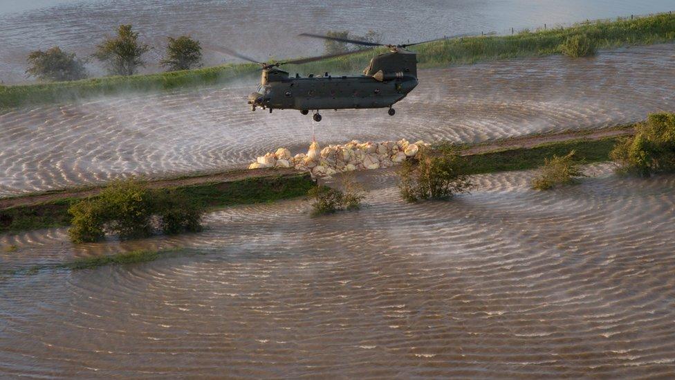 RAF Chinook helicopter dropping ballast on the breach in the River Steeping