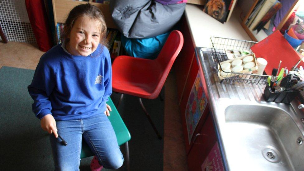 A girl sits next to art equipment.