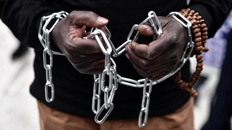 An African migrant with his hands chained, takes part in a march towards the offices of the European Union during a demonstration on December 2, 2017 in central Athens, protesting against the slavery of migrants in Libya.