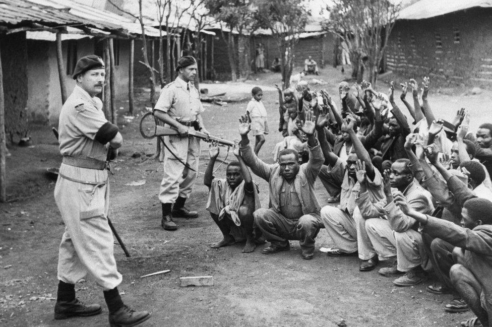 British policemen hold Mau Mau suspects at gunpoint in 1952.