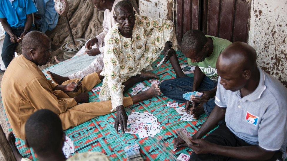 Men play a game of cards in Mbalala, Borno State northeast Nigeria on March 25, 2016. On April 14, 2014, Boko Haram militants kidnapped 276 schoolgirls from their dormitories at the Government Girls Secondary School Chibok, drawing global attention to the Islamist insurgency in northeast Nigeria.