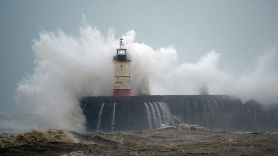 Waves crash over Newhaven Lighthouse on the south coast of England