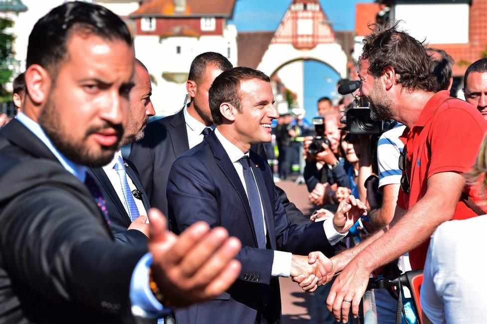 French President Emmanuel Macron (C) shakes hands with people after he voting in Le Touquet, northern France