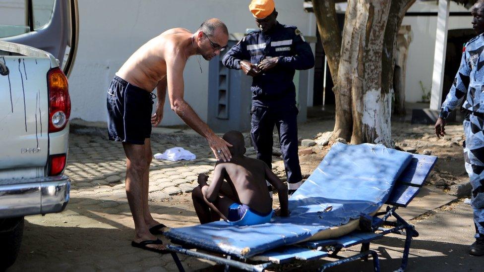 A man comforts an injured boy in Bassam, Ivory Coast, on 13 March, 2016