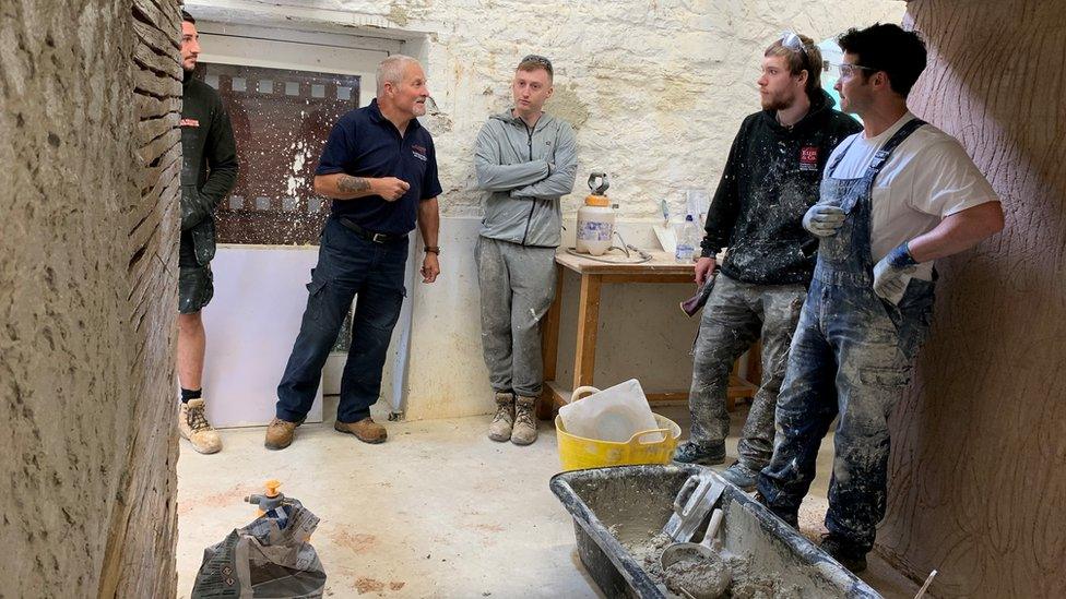 workmen applying plaster to a wall