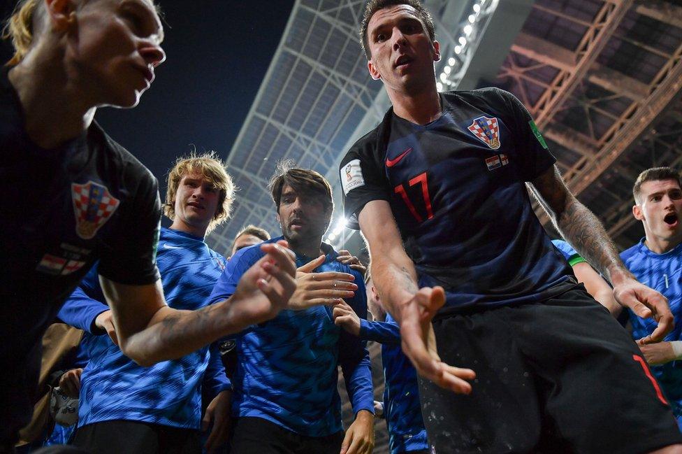 Croatia's forward Mario Mandzukic (C) offers to help AFP photographer Yuri Cortez after he fell on him with teammates while celebrating their second goal