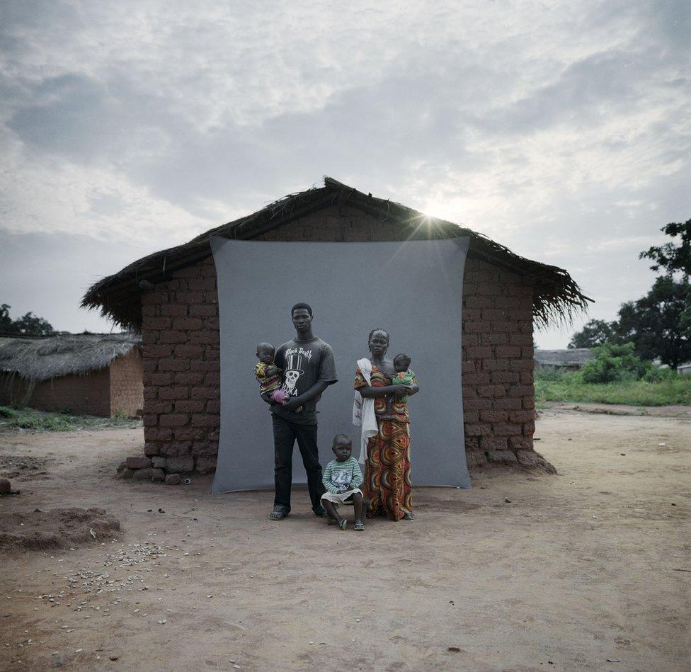 A family stand in front of their house.