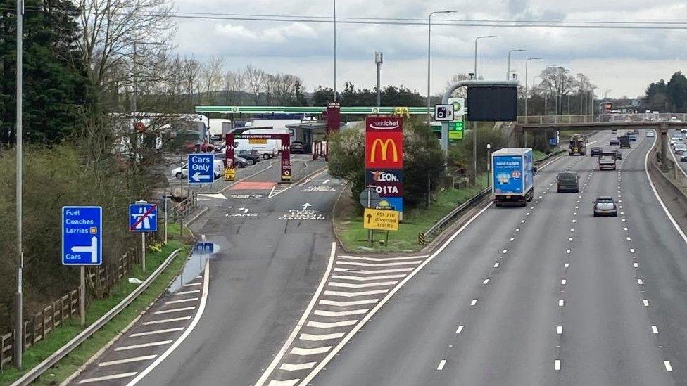 Service station entrance on southern side of the M1, showing signs for shops on the site