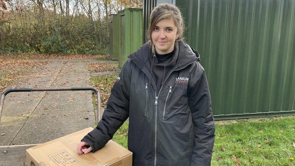 Young woman stands next to a box of fireworks