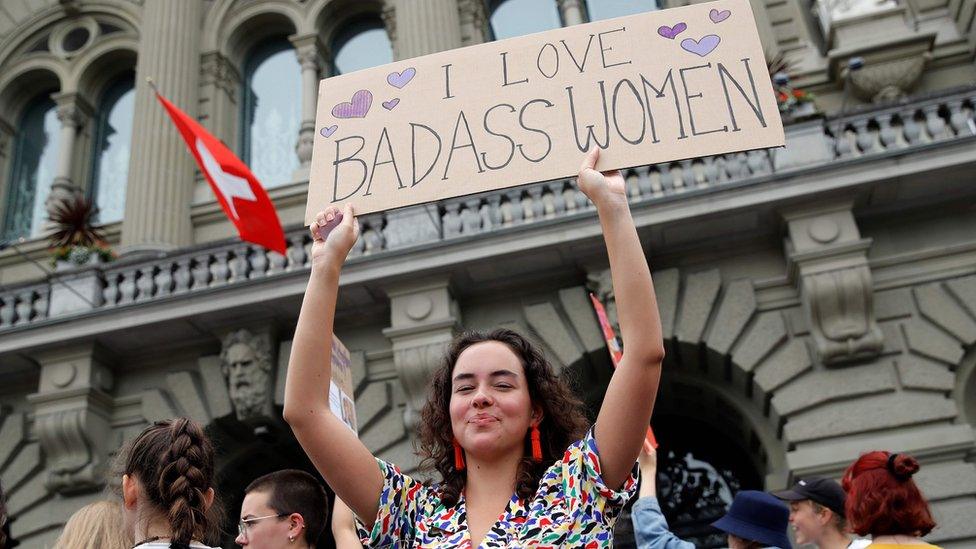 A woman holds a placard outside the federal palace in Bern during a nationwide women's strike for wage parity outside the federal palace