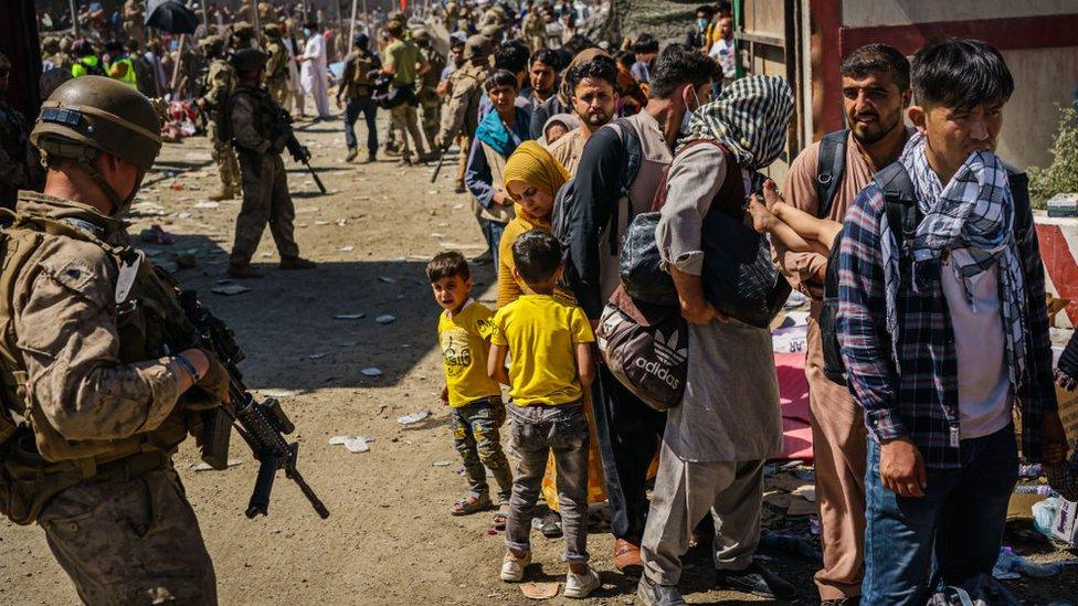 Soldiers watch over Afghan refugees waiting in line to be processed for an exit flight out of Kabul